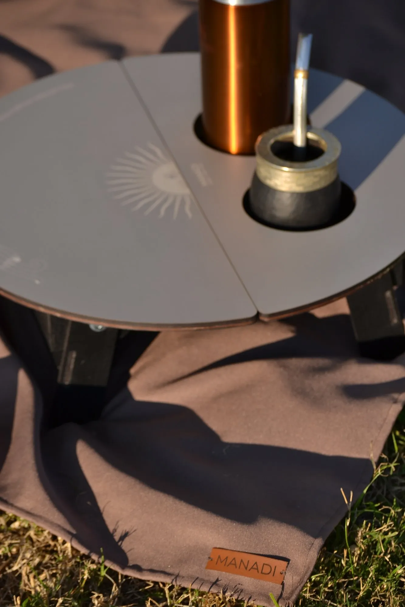Detalle de la mesa Tapir con el grabado del sol y la manta con la etiqueta de Manadi