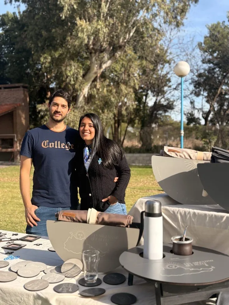 Mauro y Nadia en su puesto de feria, con las mesas materas y los posavasos sobre la mesa